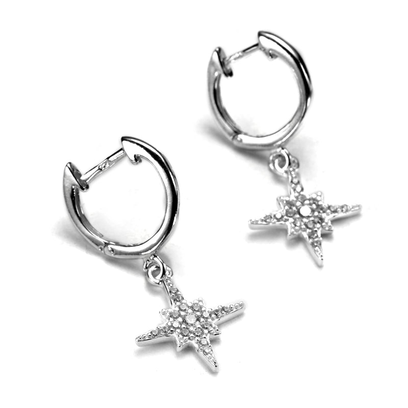 A pair of sterling silver huggie earrings with cubic zirconia starburst charms dangling from them.