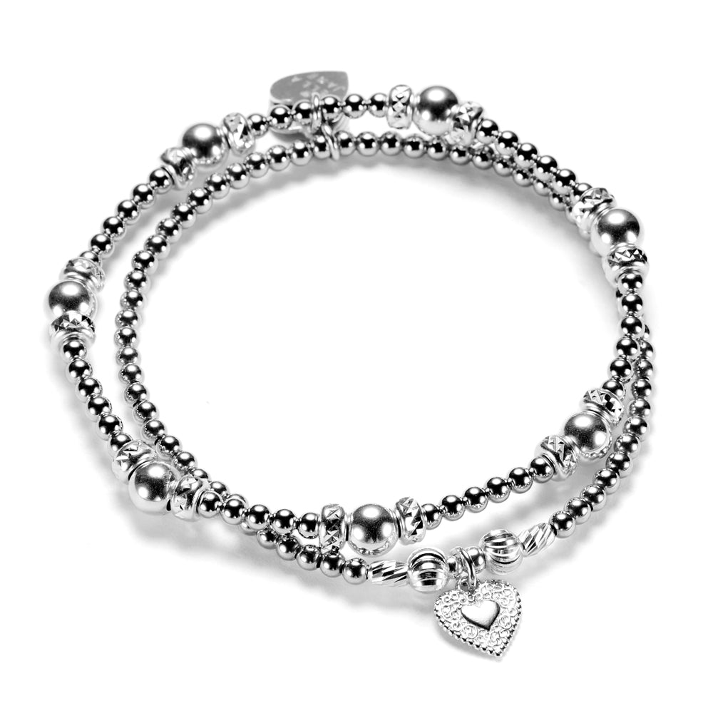 Silver beaded bracelet duo with heart charm on a white background