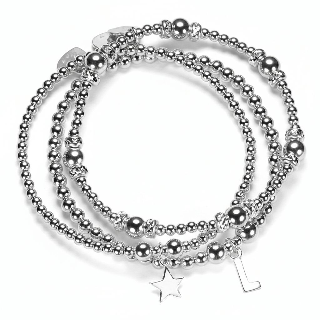Stack of silver beaded bracelets with star and initial charms on a white background