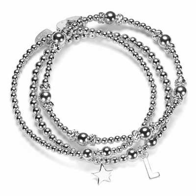 Stack of silver beaded bracelets with star and initial charms on a white background
