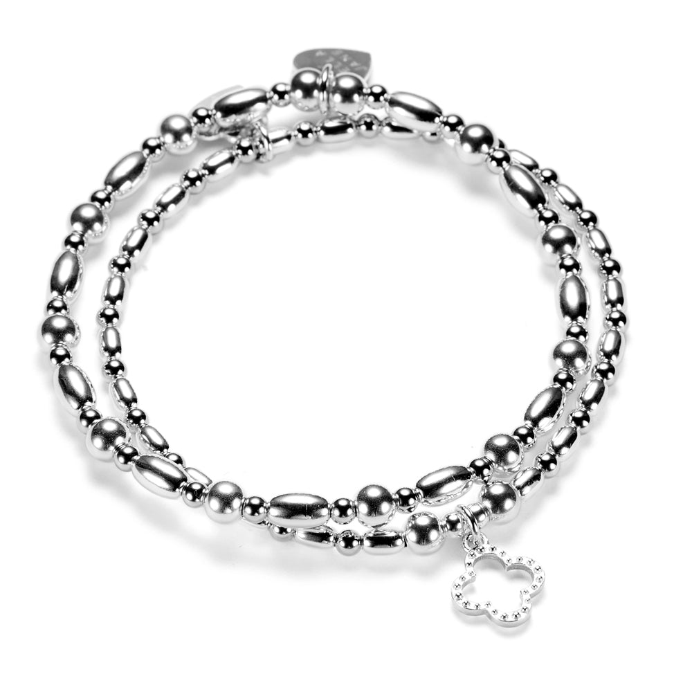 Silver beaded bracelet duo featuring an open style, studded four leaf clover charm on a white background