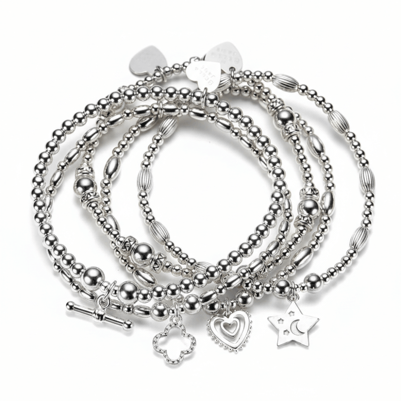 Set of 5 silver beaded bracelets with heart, star, clover and t-bar charms on a white background