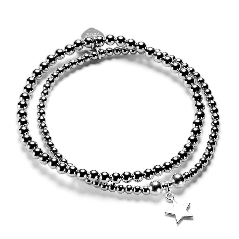 A silver stacking bracelet duo with one plain stacking bracelet and one featuring a silver star charm, on a white background