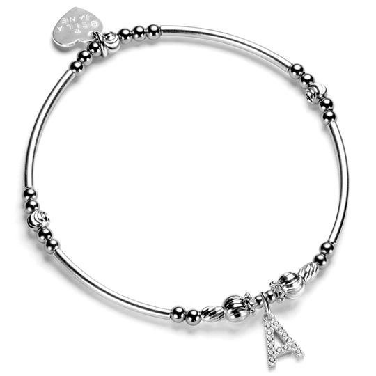 A sterling silver bracelet with a mix of round and noodle-shaped beads, featuring a cubic zirconia initial charm and a signature sterling silver Bella Jane heart tag.