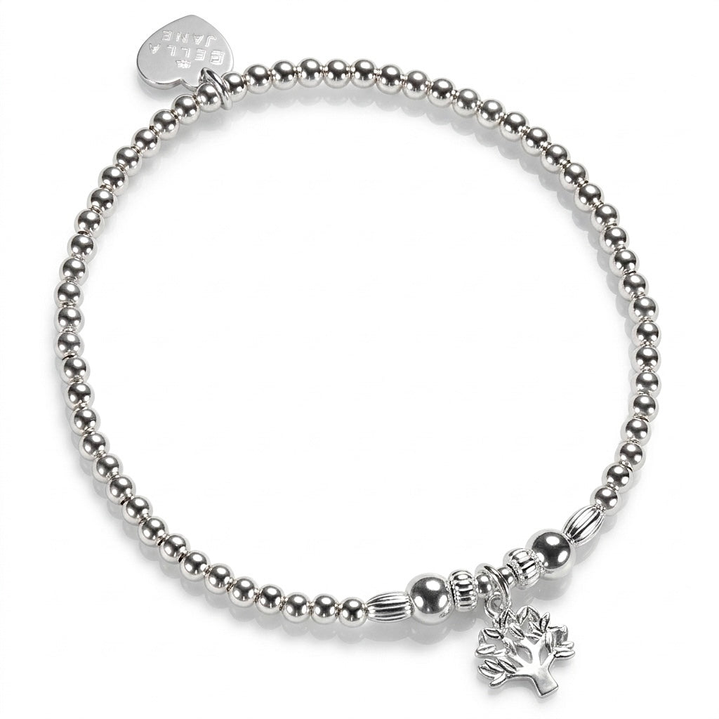 A silver beaded stretch bracelet with a small tree of life charm, with a Bella Jane silver heart tag at the back, against a white background.