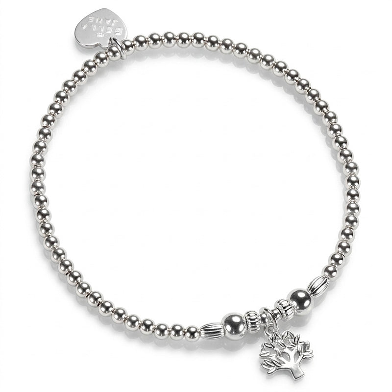 A silver beaded stretch bracelet with a small tree of life charm, with a Bella Jane silver heart tag at the back, against a white background.