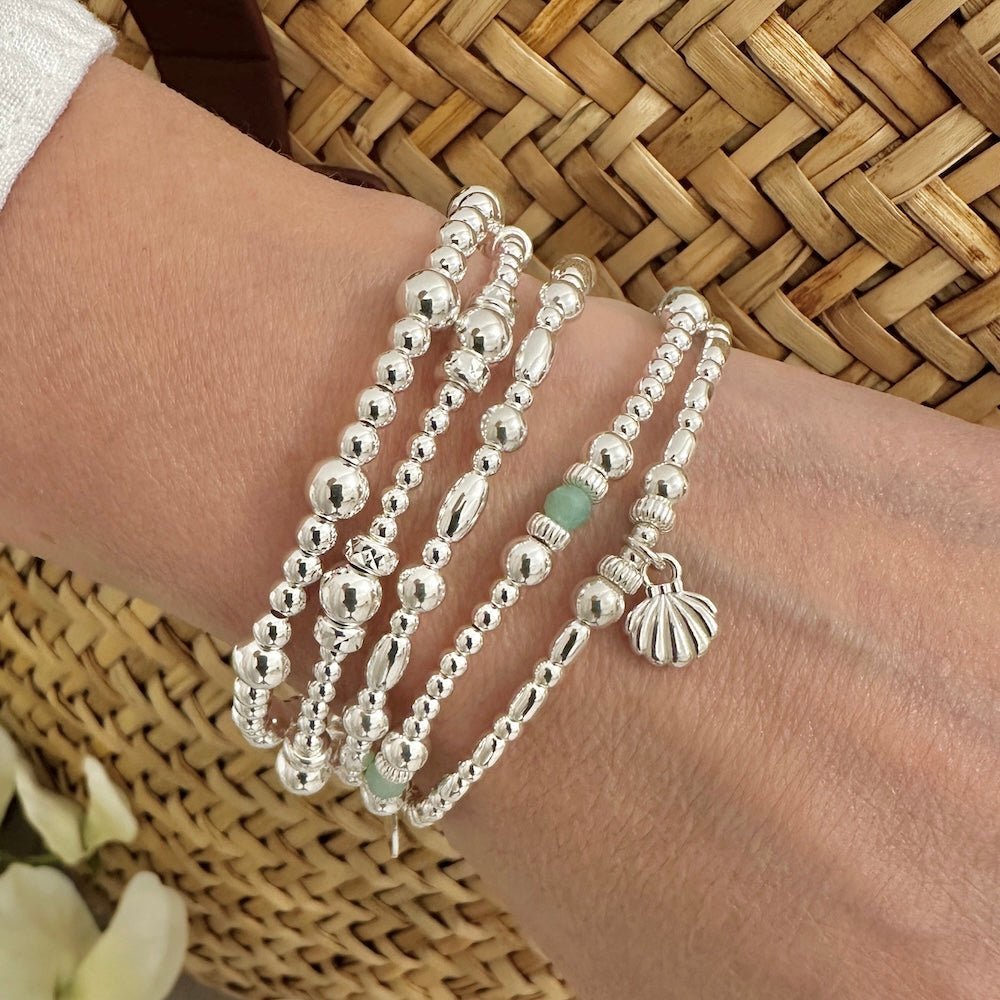 Silver beaded bracelets on a wrist with a woven background