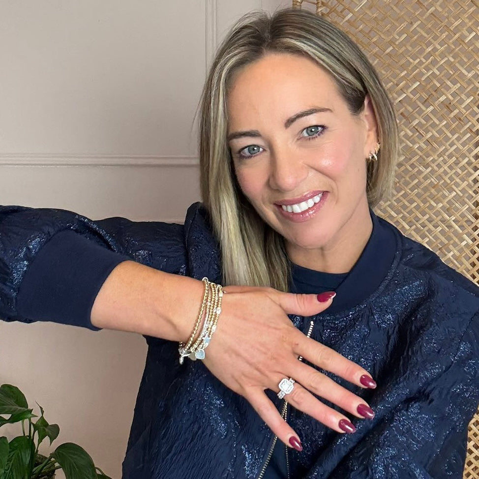 Woman in a blue sequin outfit showing off a Bella Jane gold and silver mixed metal beaded bracelet stack.