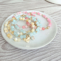 Set of Bella Jane Summer 2026 pastel coloured beaded stacking bracelets on a white dish with a wooden background