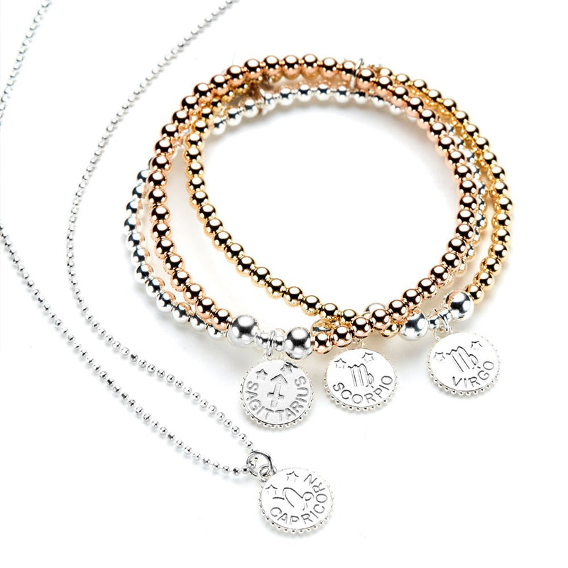 Set of gold and silver beaded bracelets with zodiac charms, with a Capricorn Zodiac necklace on a white background