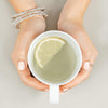 A set of three sterling silver stacking bracelets modelled on a wrist holding a mug of lemon water