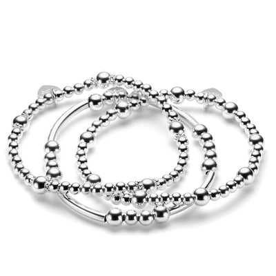 A set of three sterling silver beaded stacking bracelets laid out on a white surface.