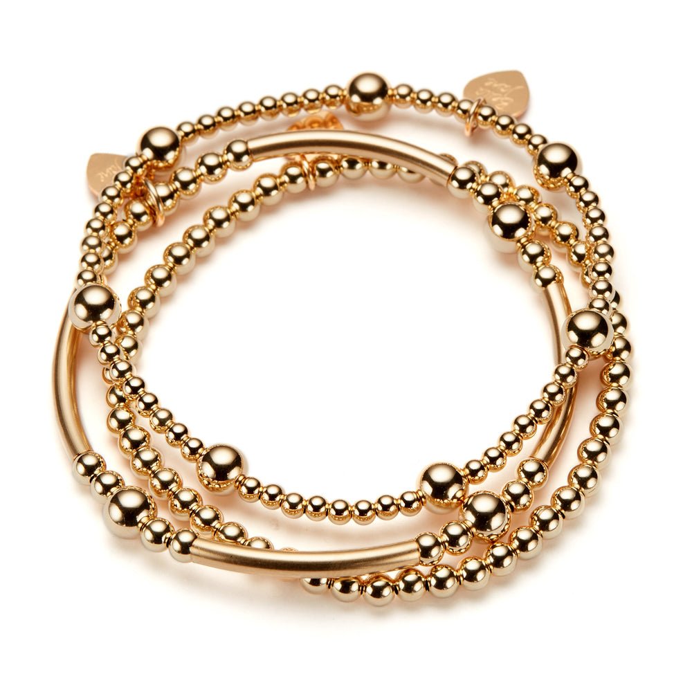 A stack of three gold-filled beaded stacking bracelets on a white background
