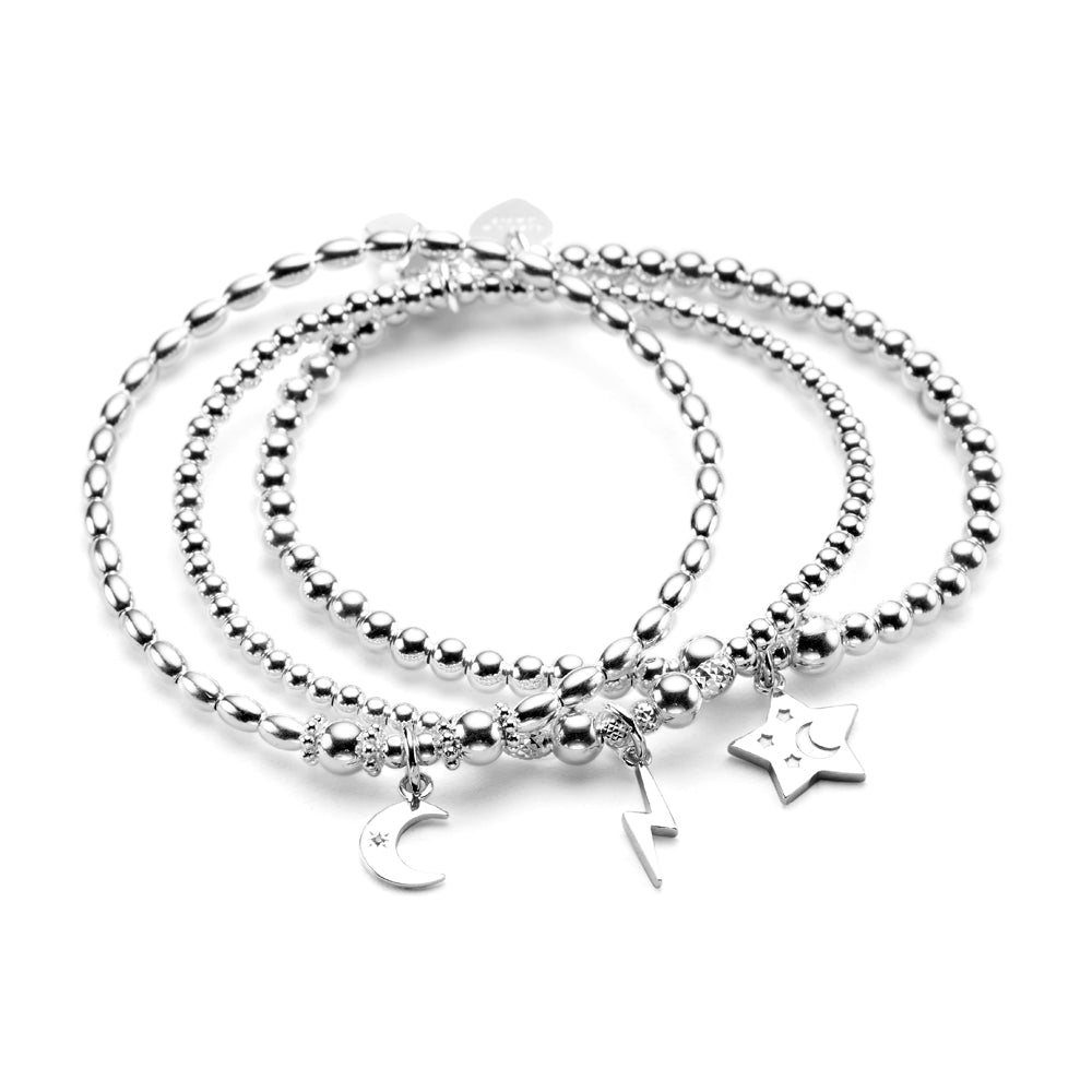 Three sterling silver beaded bracelets stacked on top of each other, featuring a moon, lightning bolt and star charms, against a white background.