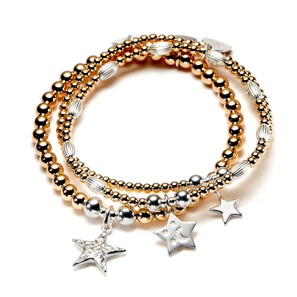 Stack of gold and silver beaded bracelets with star charms on a white background