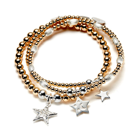 Stack of gold and silver beaded bracelets with star charms on a white background