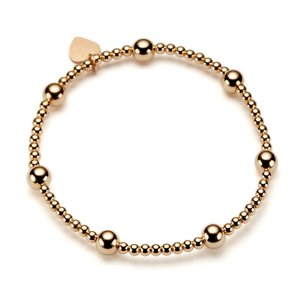 A gold-filled beaded stacking bracelet featuring a branded Bella Jane heart tag