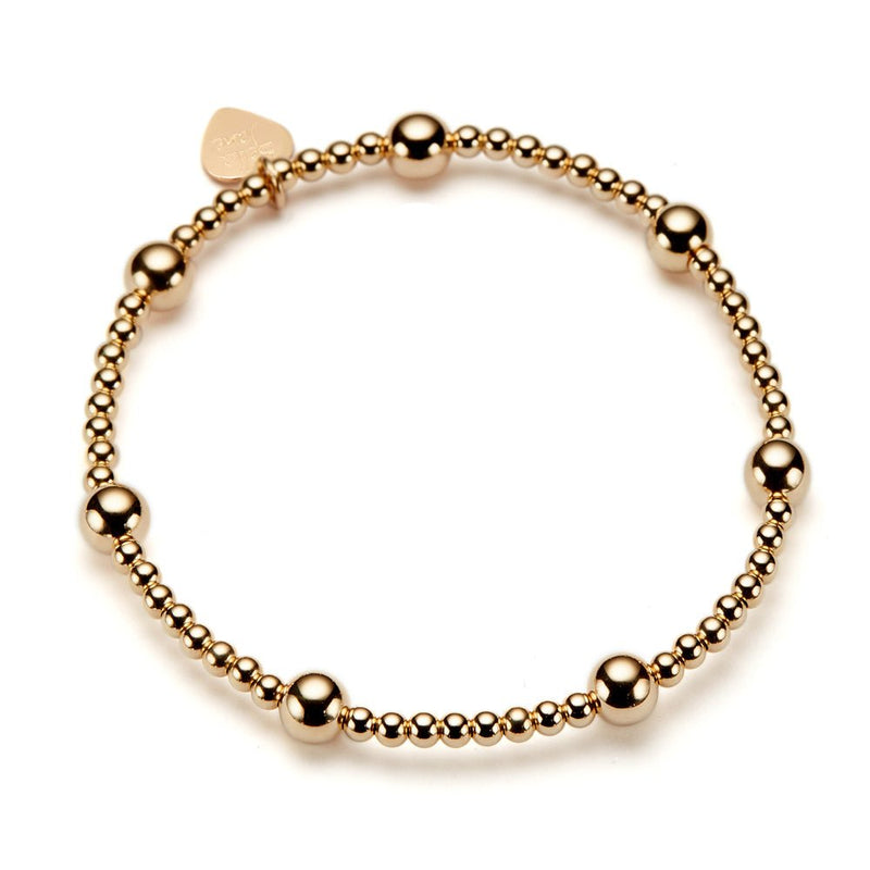 A gold-filled beaded stacking bracelet featuring a branded Bella Jane heart tag