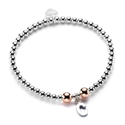 A sterling silver bracelet with rose gold-filled beads and a silver initial charm, displayed against a white background.