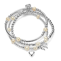 Stack of silver and pearl bracelets with silver heart and bow charms, on a white background