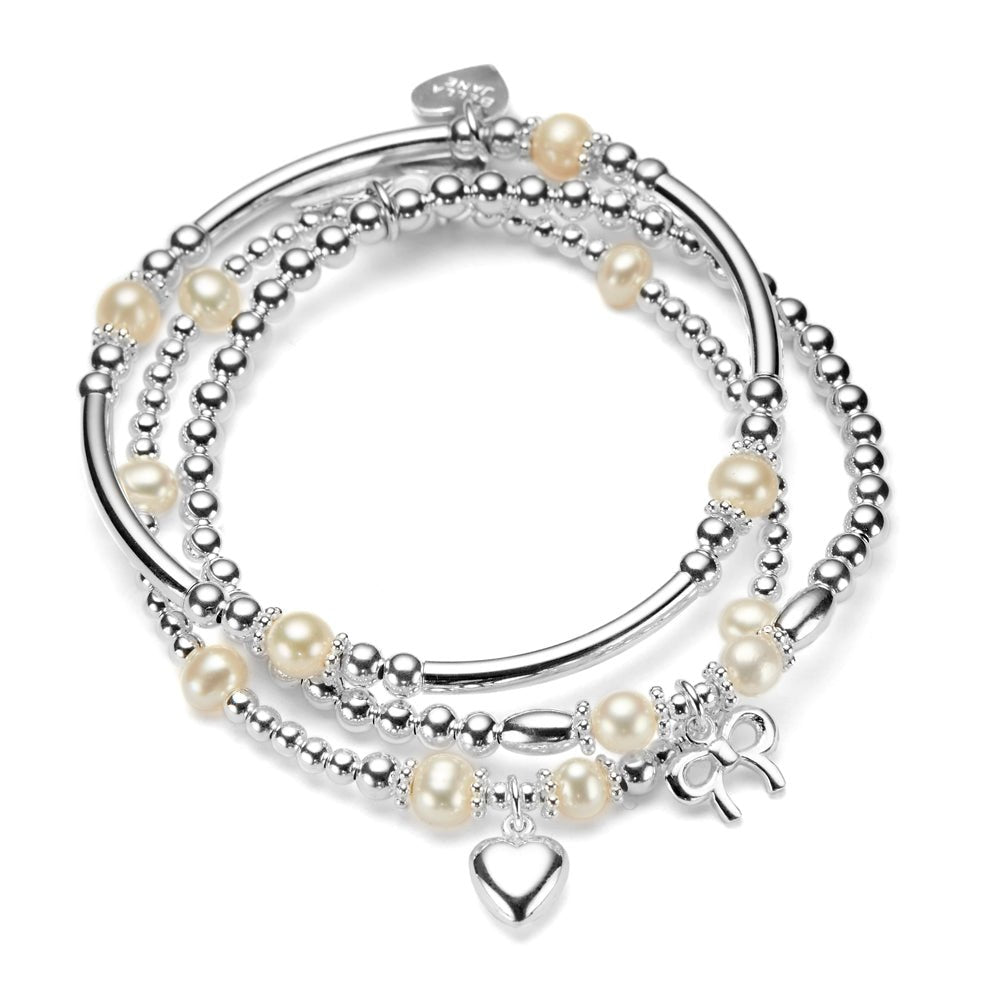 Stack of silver and pearl bracelets with silver heart and bow charms, on a white background