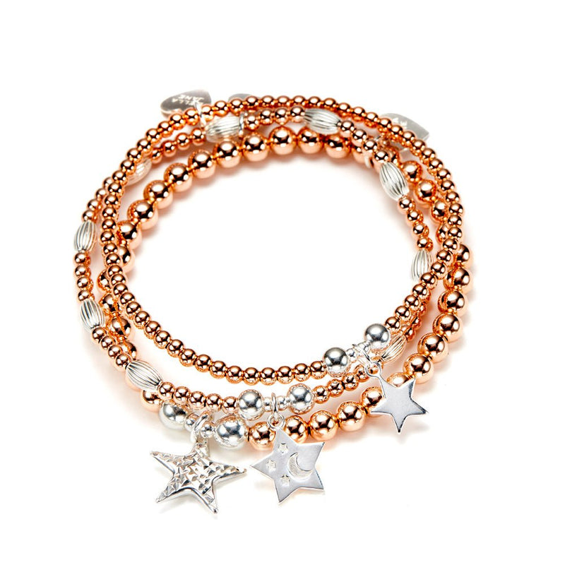 Stack of rose gold and silver beaded bracelets with star charms on a white background