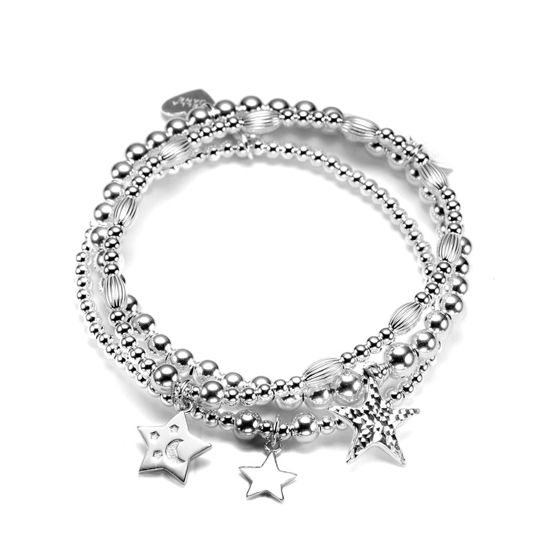 A stack of three sterling silver bracelets with star charms, against a white background.