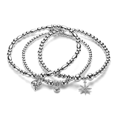 a close up of 3 silver beaded bracelets with sparkly charms on a white background.