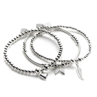 A set of three sterling silver bracelets stacked together, featuring charms including a feather, heart and angel wings.