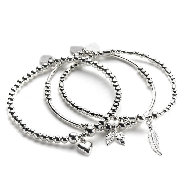 A set of three sterling silver bracelets stacked together, featuring charms including a feather, heart and angel wings.