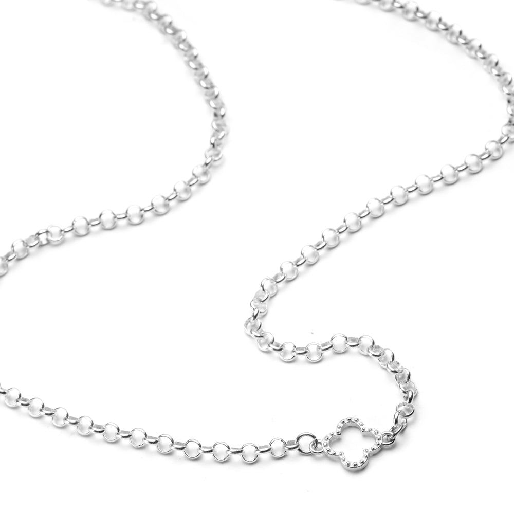 A sterling silver belcher chain with open studded clover charm in centre of the chain, on a white background